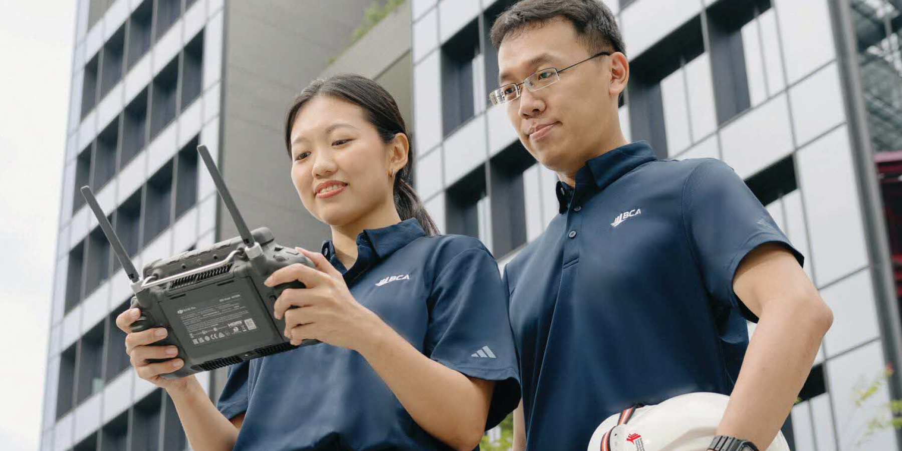 BCA officers operate a drone controller to inspect a building facade.